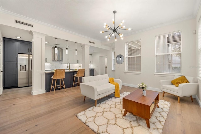 living room featuring light wood-type flooring, visible vents, a chandelier, and ornamental molding