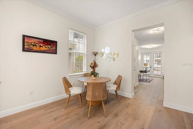 dining room with light wood-style floors, plenty of natural light, ornamental molding, and baseboards