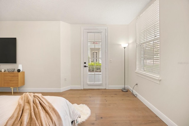 interior space featuring light wood-style flooring, baseboards, and a textured ceiling