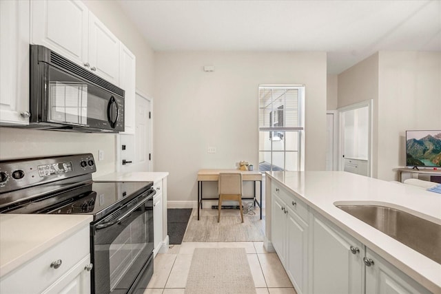 kitchen with light tile patterned floors, light countertops, white cabinets, a sink, and black appliances