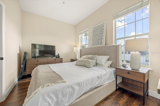 bedroom with vaulted ceiling, dark wood finished floors, and baseboards