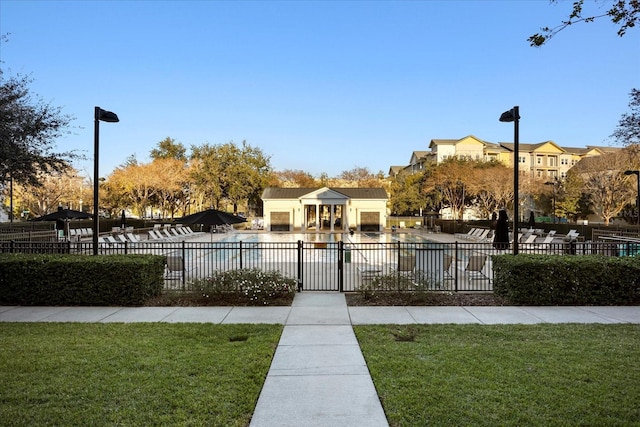 view of community with a swimming pool, fence, and a lawn