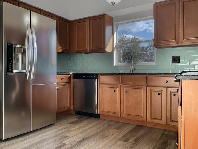 kitchen with appliances with stainless steel finishes, backsplash, and light wood-style flooring