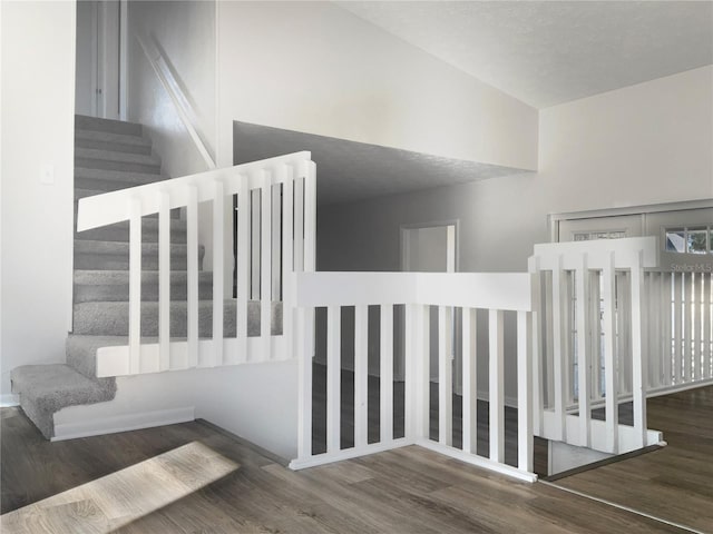 staircase with a textured ceiling and wood finished floors