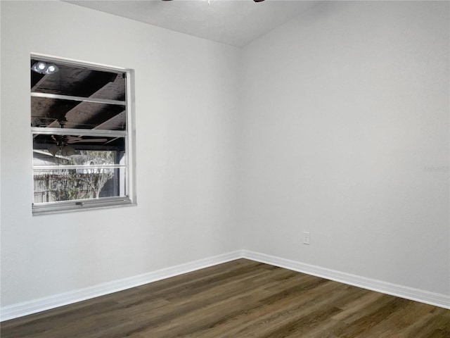 spare room with dark wood-type flooring, a ceiling fan, and baseboards