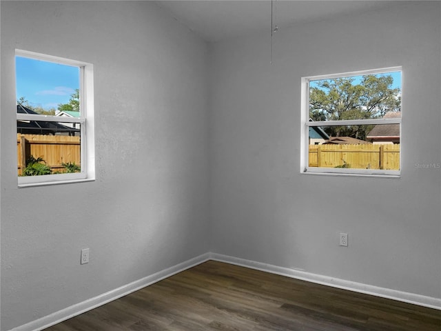 spare room featuring dark wood finished floors and baseboards