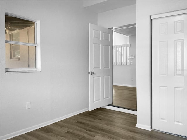 unfurnished bedroom with dark wood-style floors, a closet, and baseboards