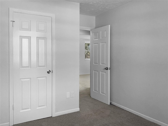 unfurnished bedroom featuring a textured ceiling, baseboards, and carpet flooring