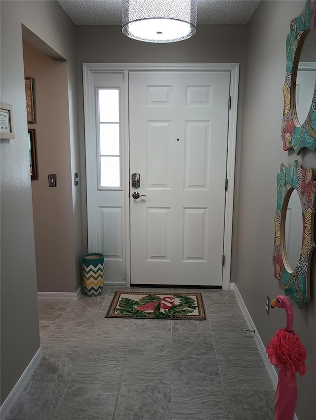 doorway to outside featuring baseboards and a textured ceiling