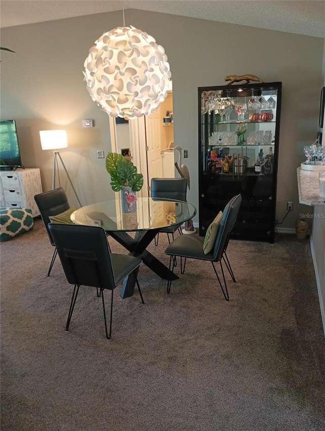 carpeted dining room featuring vaulted ceiling