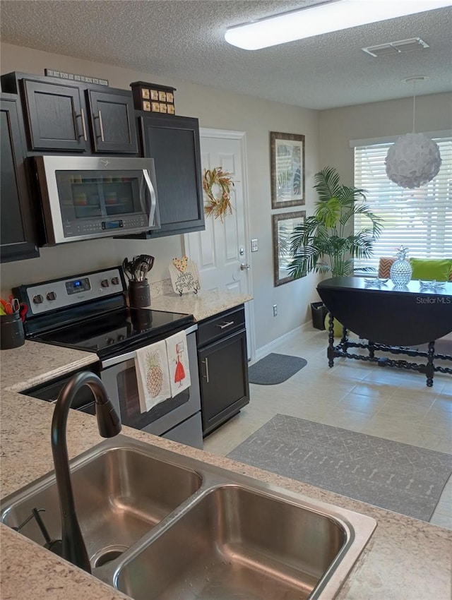 kitchen featuring a sink, stainless steel appliances, a textured ceiling, and light countertops