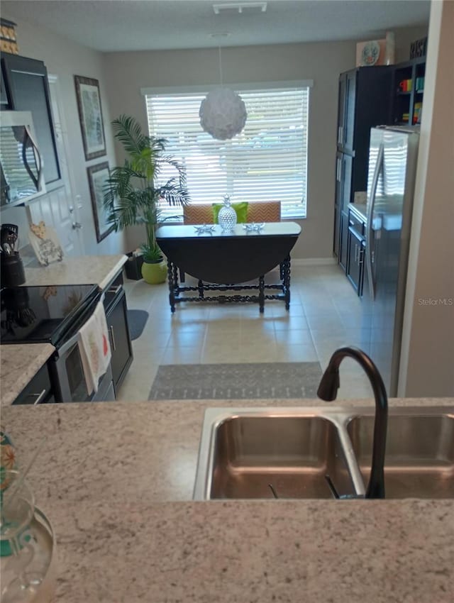 kitchen with light tile patterned floors, stainless steel appliances, and a sink