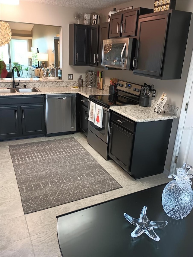 kitchen with a textured ceiling, appliances with stainless steel finishes, and a sink