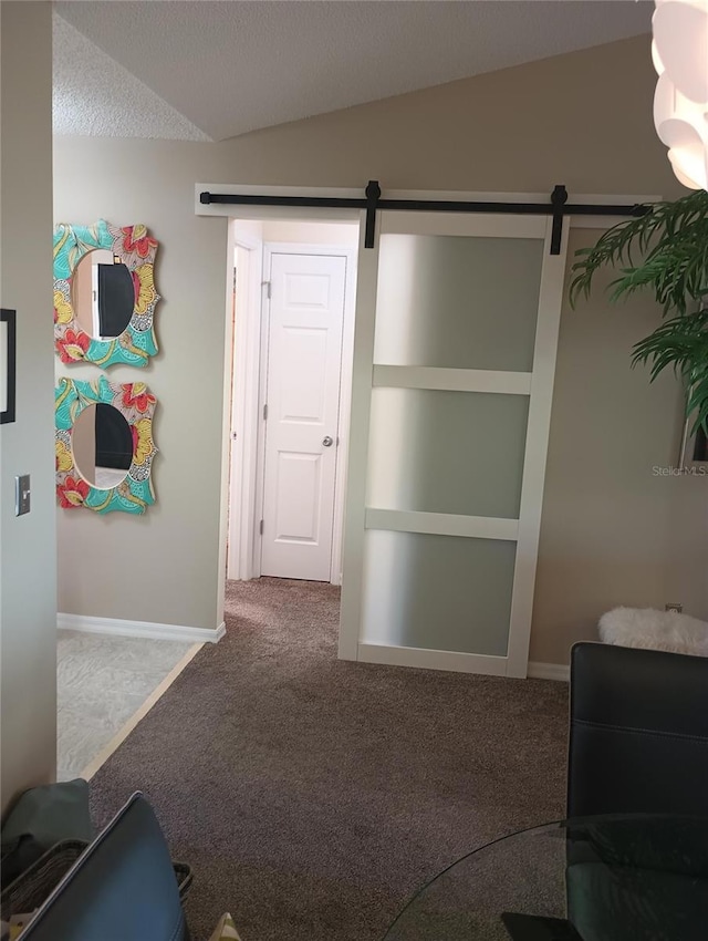 hallway with lofted ceiling, a barn door, a textured ceiling, and carpet