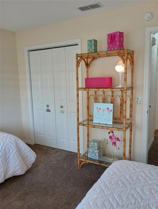 bedroom with carpet, a closet, visible vents, and a textured ceiling