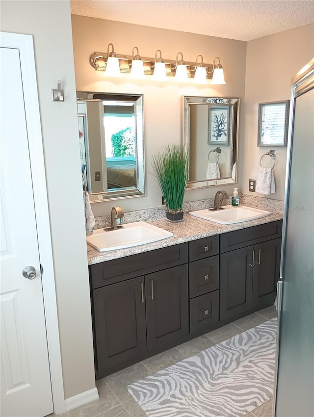 bathroom with double vanity, tile patterned flooring, a textured ceiling, and a sink