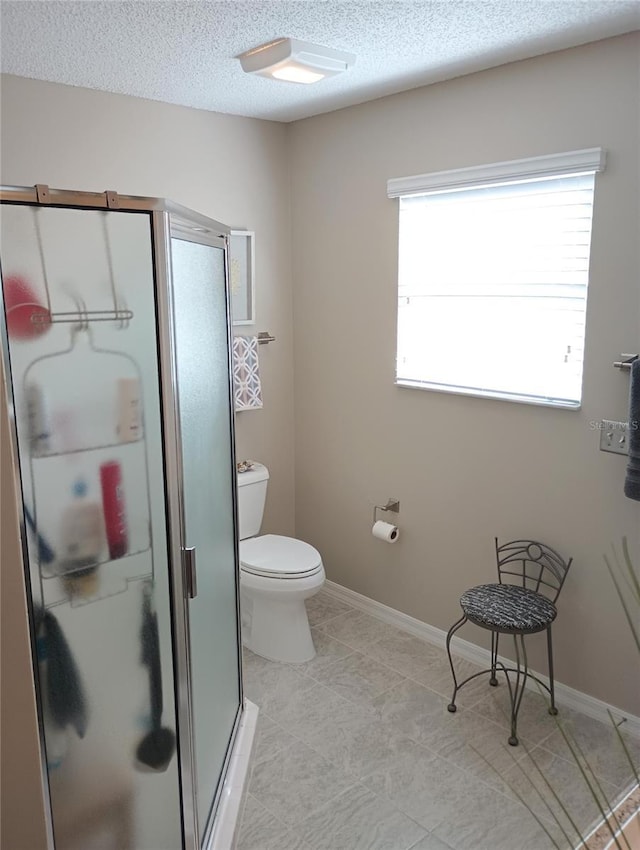 full bath with a textured ceiling, toilet, baseboards, a shower stall, and tile patterned floors