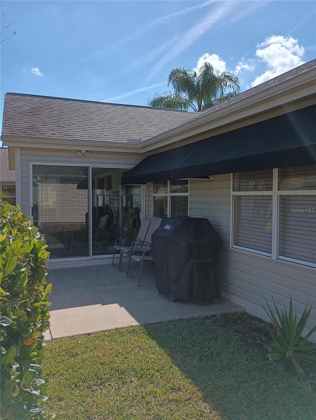 rear view of property with a patio area and roof with shingles