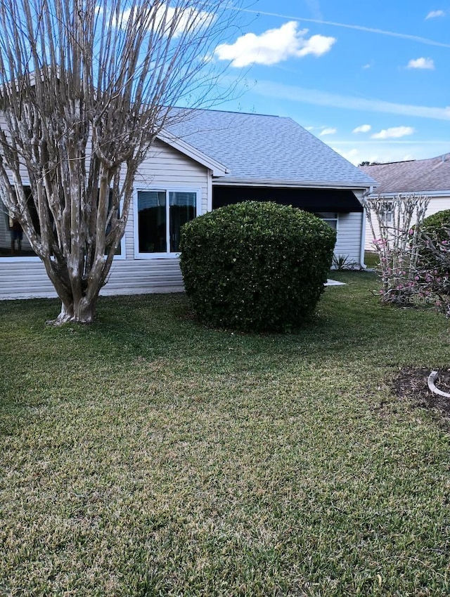 view of home's exterior with a yard and roof with shingles