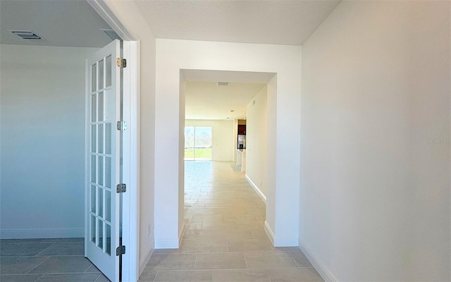 corridor with baseboards and visible vents