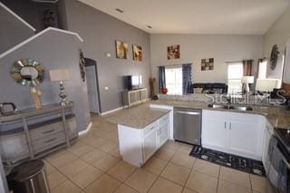 954 Lockbreeze Dr, Davenport, FL 33897 - kitchen featuring stainless steel dishwasher, lofted ceiling, light tile patterned flooring, a peninsula, and white cabinetry