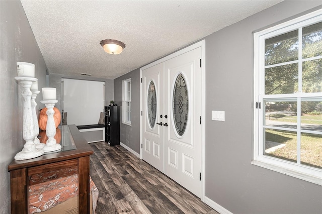 entryway with a textured ceiling, baseboards, and dark wood-type flooring