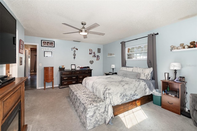 bedroom featuring a ceiling fan, a textured ceiling, and light colored carpet