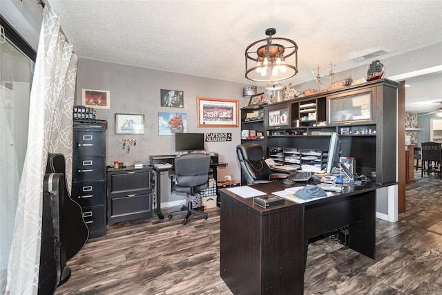 home office featuring dark wood-type flooring, visible vents, a textured ceiling, and an inviting chandelier