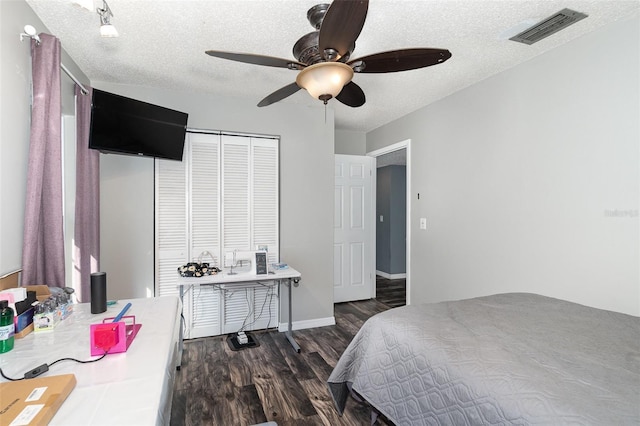 bedroom featuring visible vents, dark wood finished floors, a ceiling fan, a textured ceiling, and a closet