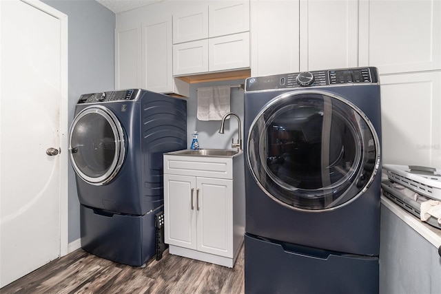 washroom with cabinet space, dark wood-type flooring, a sink, a textured ceiling, and independent washer and dryer