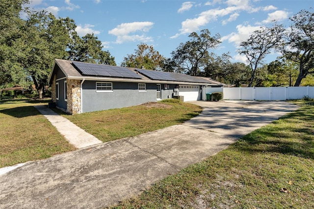 view of front facade featuring a garage, stone siding, concrete driveway, roof mounted solar panels, and a front lawn