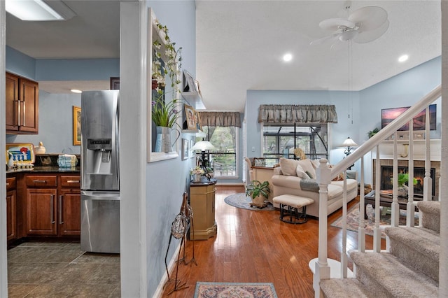 kitchen featuring dark wood-type flooring, brown cabinetry, dark countertops, and stainless steel fridge