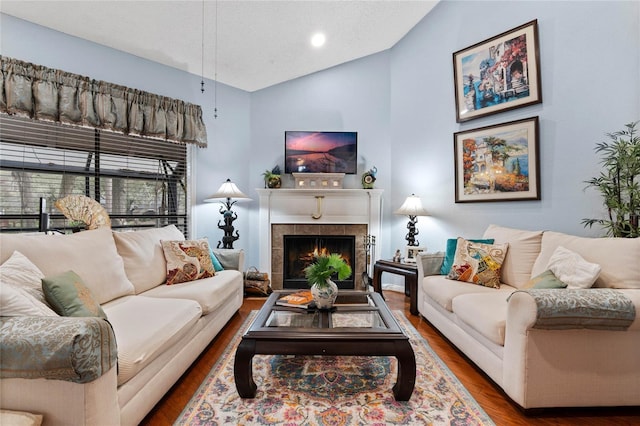 living room featuring high vaulted ceiling, a fireplace, and wood finished floors