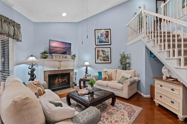 living room with a fireplace, wood finished floors, high vaulted ceiling, baseboards, and stairs