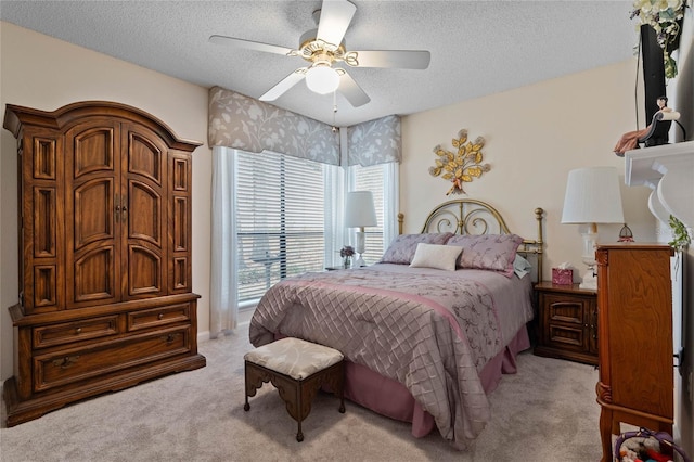 bedroom with a ceiling fan, light colored carpet, and a textured ceiling