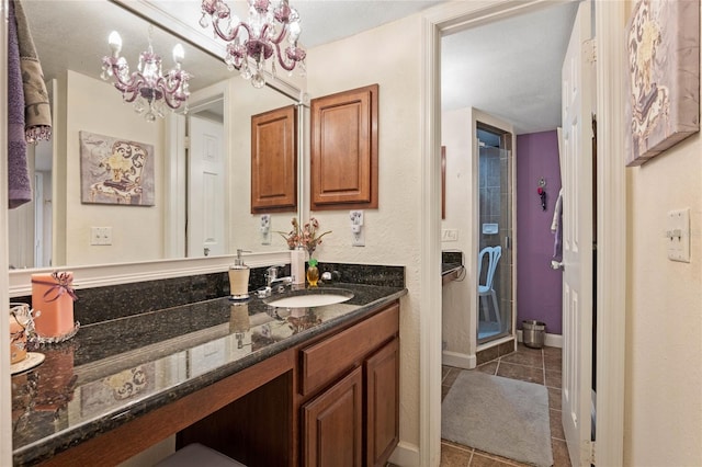 bathroom with a stall shower, baseboards, tile patterned floors, an inviting chandelier, and vanity