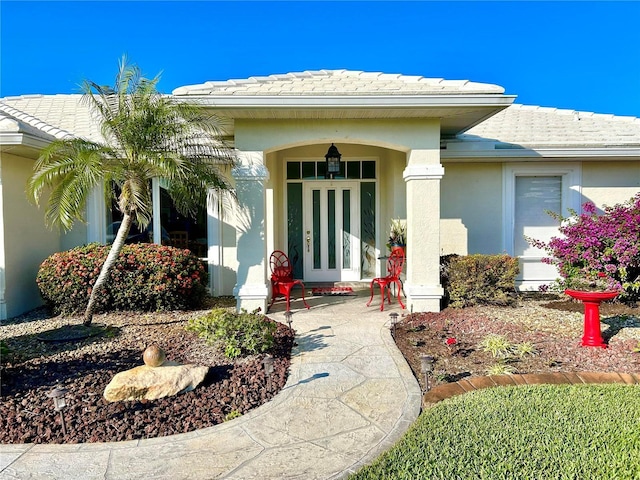doorway to property with a tiled roof, stucco siding, and french doors