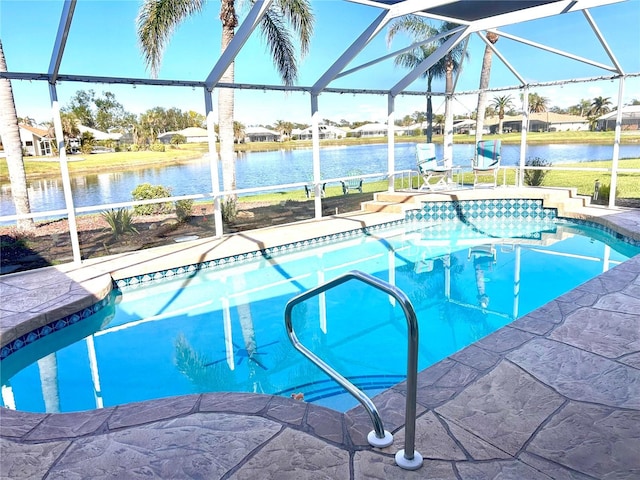 outdoor pool with glass enclosure, a water view, and a patio
