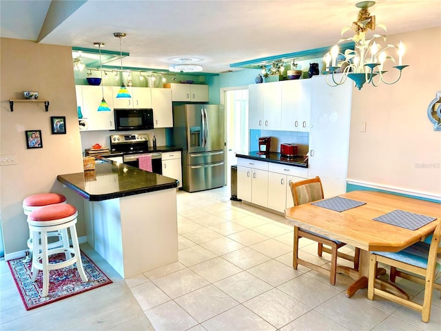 kitchen with appliances with stainless steel finishes, a peninsula, dark countertops, pendant lighting, and light tile patterned floors