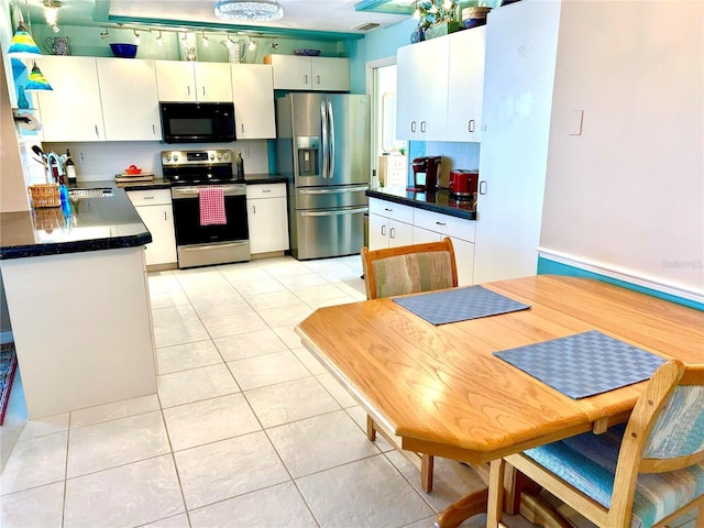 kitchen featuring stainless steel appliances, dark countertops, white cabinetry, and light tile patterned floors