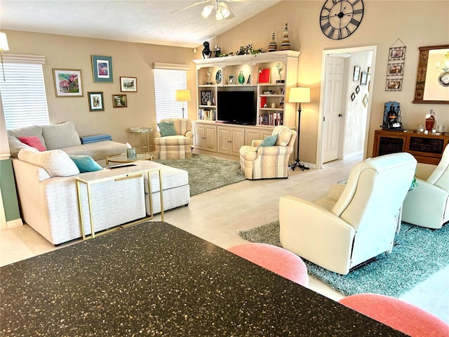 living room featuring ceiling fan, lofted ceiling, and baseboards