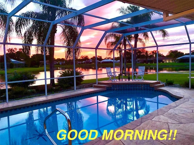 outdoor pool featuring glass enclosure, a water view, a patio, and a lawn