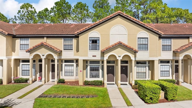 view of front of house with a front lawn, a tiled roof, and stucco siding