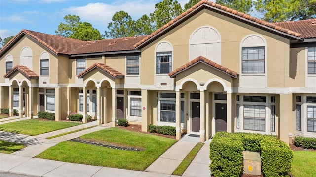 view of front of home with stucco siding, a front yard, and a tiled roof