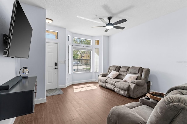 living room featuring a ceiling fan, wood finished floors, baseboards, and a textured ceiling