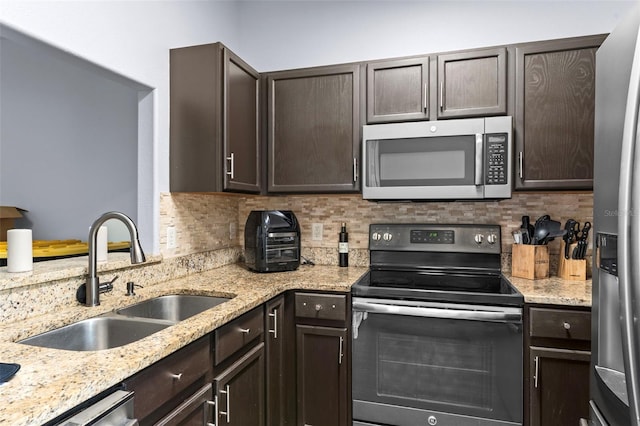 kitchen with decorative backsplash, dark brown cabinets, appliances with stainless steel finishes, and a sink