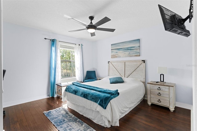 bedroom with ceiling fan, wood finished floors, baseboards, and a textured ceiling