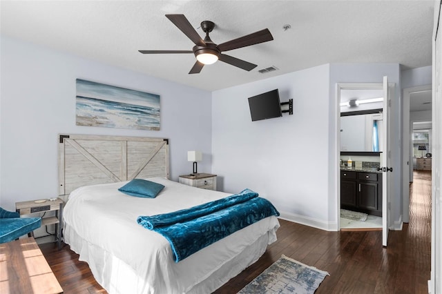 bedroom with dark wood-type flooring, a ceiling fan, a textured ceiling, ensuite bath, and baseboards