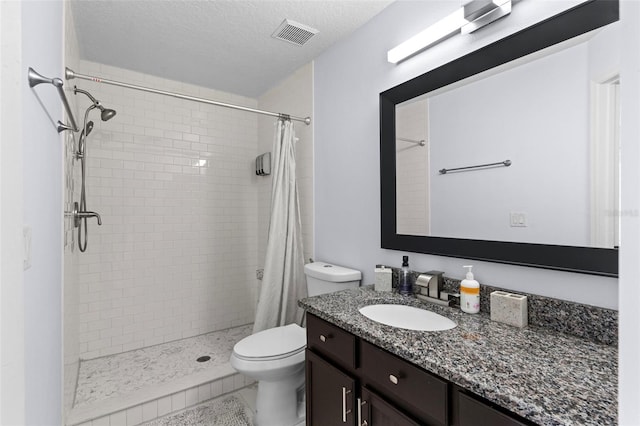 bathroom featuring visible vents, toilet, a shower stall, and a textured ceiling