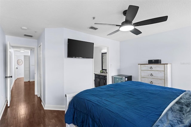 bedroom with visible vents, baseboards, dark wood-type flooring, and a textured ceiling